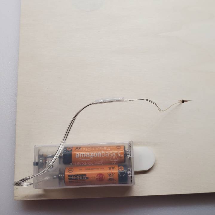hole in back of wood panel showing light battery pack