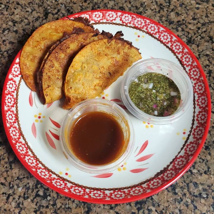 plate containing 3 beef birria tacos with birria juice and cilantro dressing